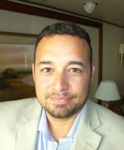 A man in a suit and tie standing next to a lamp.